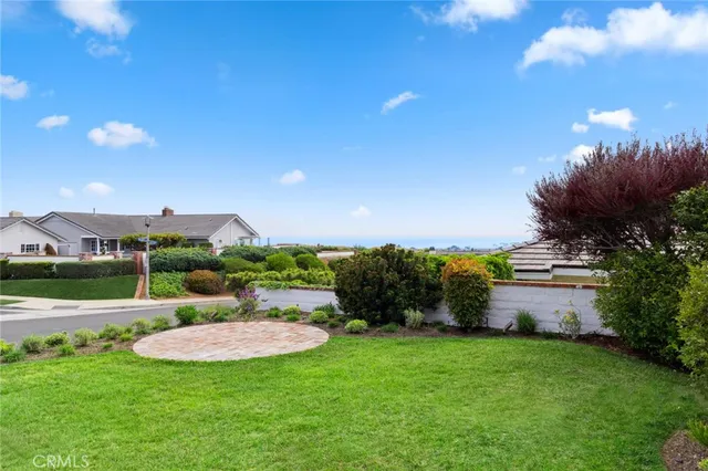 a view of a white house with a big yard and potted plants