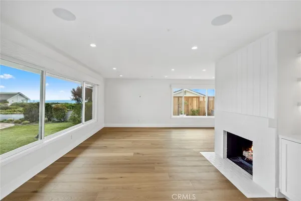 a view of an empty room with wooden floor and a fireplace