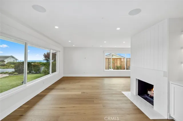 a view of an empty room with wooden floor and a fireplace