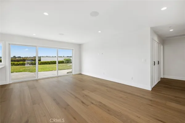 a view of an empty room with wooden floor and a fireplace