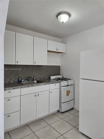 a kitchen with granite countertop white cabinets and white appliances