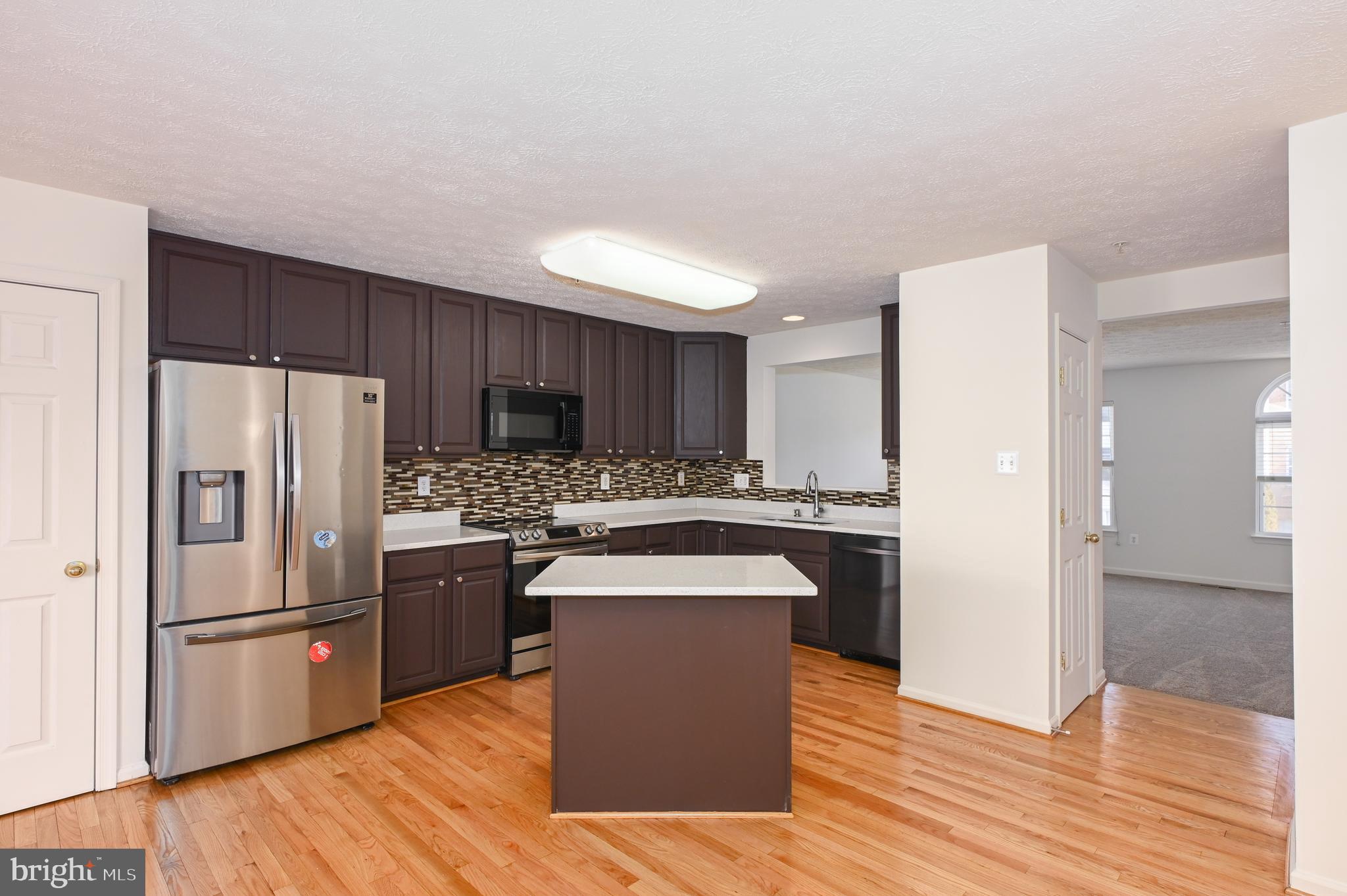 9871 Decatur Road Baltimore, MD 21220 - Photo 23 of 31 a kitchen with stainless steel appliances granite countertop a refrigerator a sink dishwasher a stove with wooden floor and cabinets