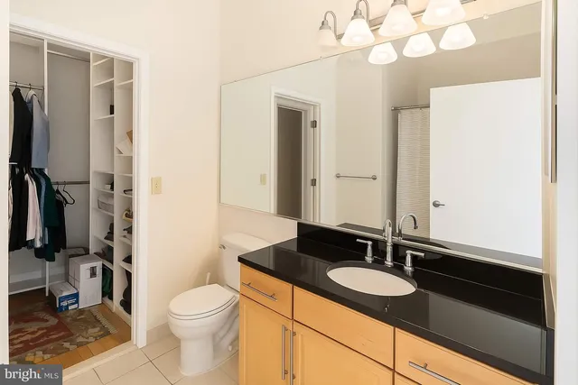 a bathroom with a granite countertop sink a toilet and a mirror