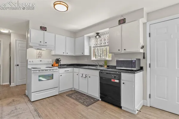 a kitchen with stainless steel appliances granite countertop a stove a sink and white cabinets