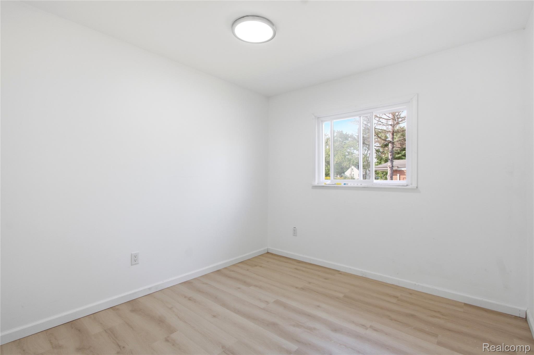 17544 Evergreen Road Detroit, MI 48219 - Photo 12 of 16 White walls, wood-finish flooring, flush mount lighting fixture, and a single window
