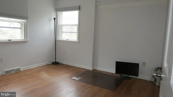 a view of a big room with wooden floor and windows
