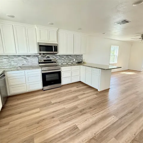 a kitchen with granite countertop a stove top oven and cabinets