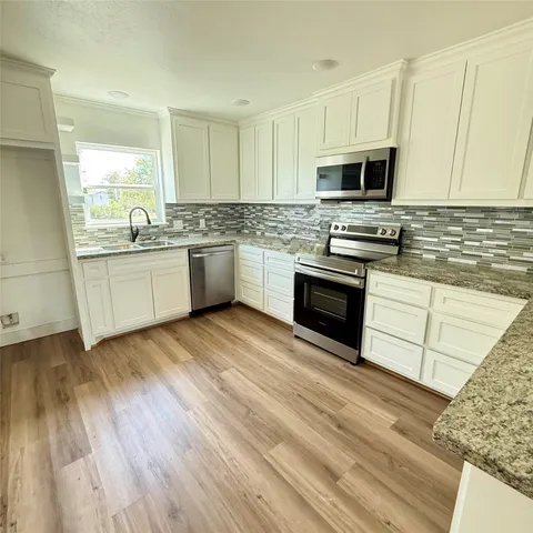 a kitchen with granite countertop a sink cabinets and stainless steel appliances