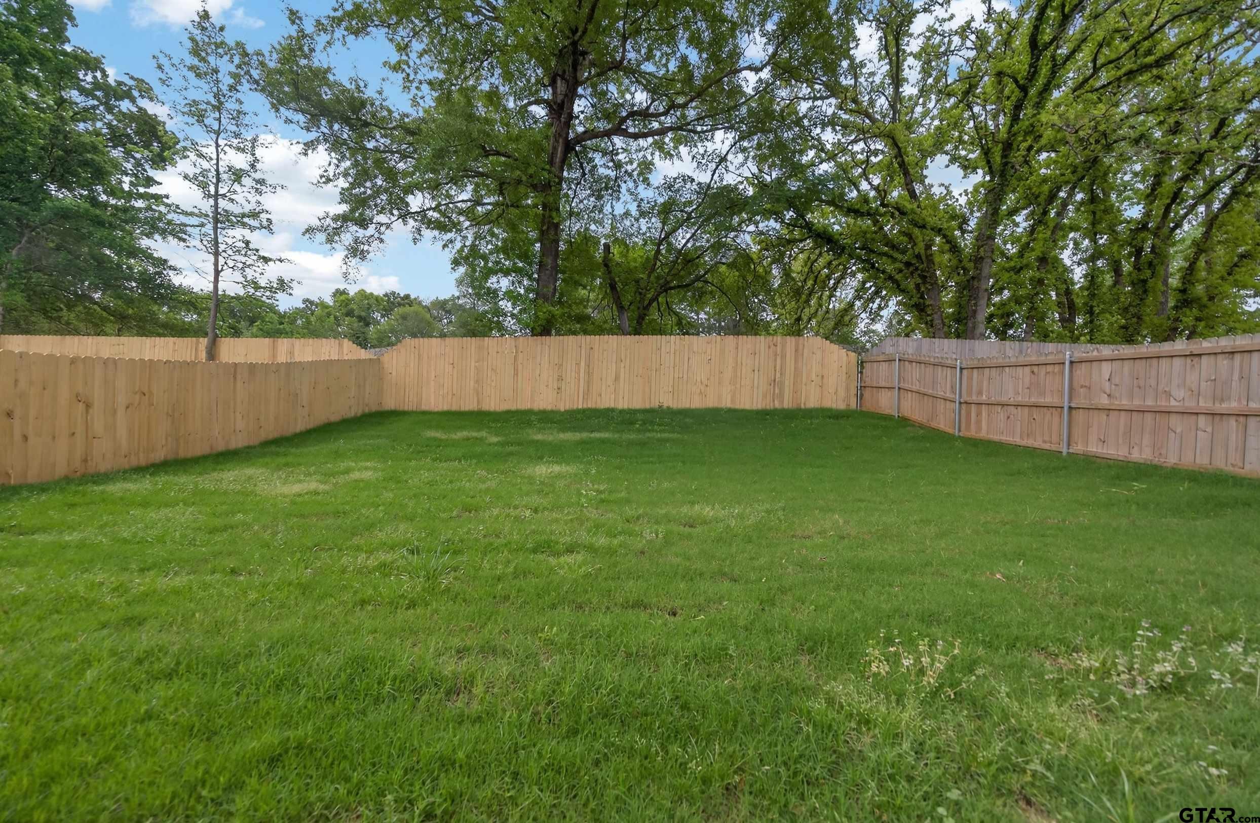 3049 Guinn Farms Road Tyler, TX 75707 - Photo 41 of 43 a view of a backyard with a large tree and wooden fence