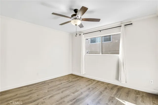 an empty room with wooden floor closet and fan