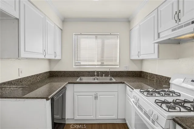 a kitchen with granite countertop a sink stove and cabinets