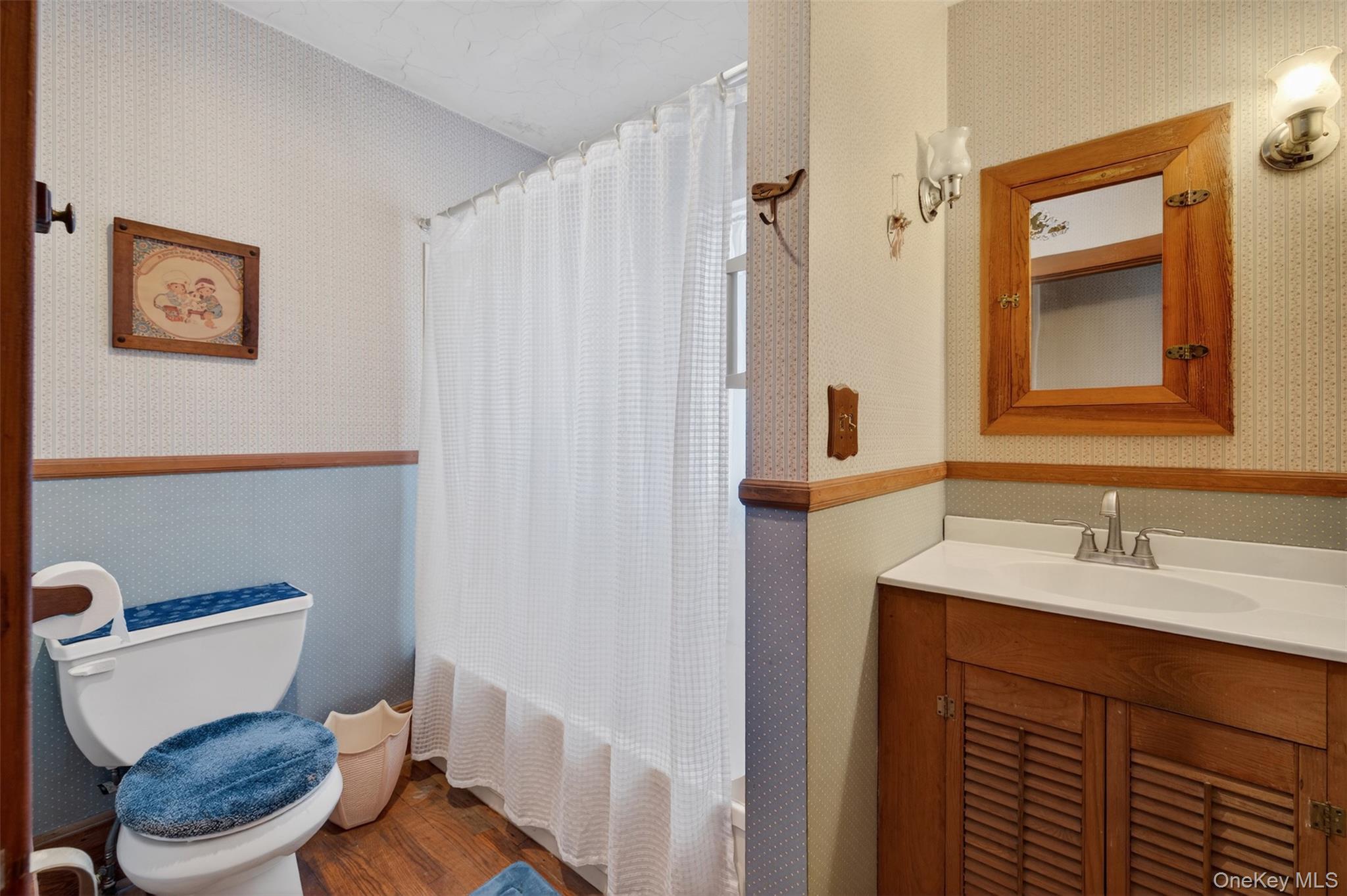 21 Innis Avenue Newburgh, NY 12550 - Photo 19 of 22 a bathroom with a sink a toilet a mirror and shower curtain