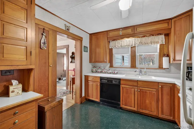 a view of a kitchen with a sink and dishwasher wooden cabinets with a large window