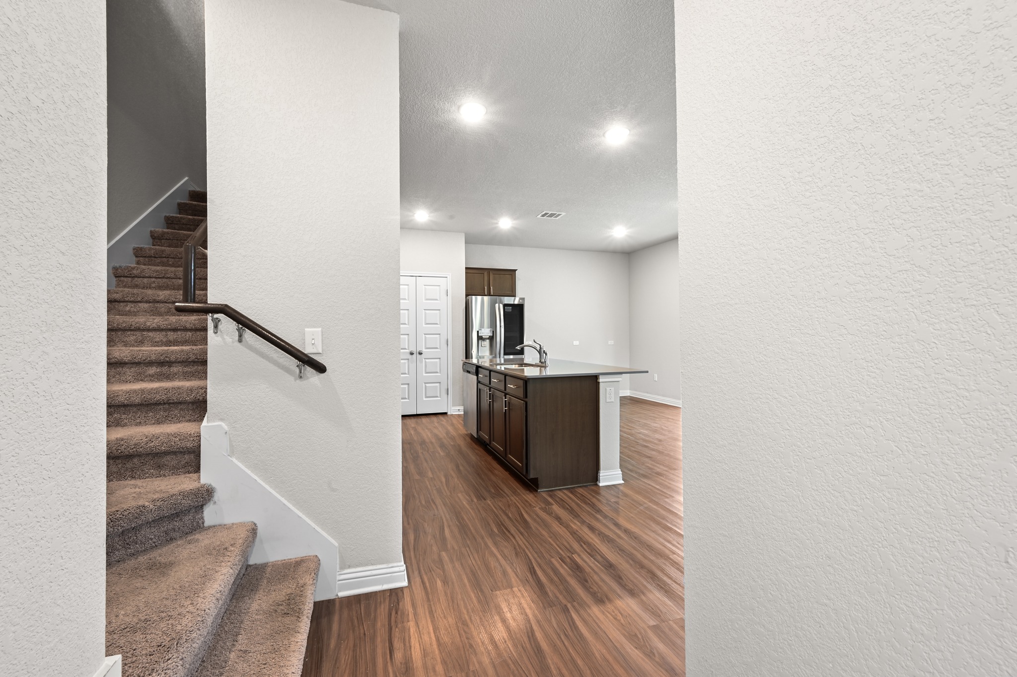 8201 Frida Bend Austin, TX 78744 - Photo 8 of 29 A vibrant kitchen island serves as a central hub, complementing the rich wood flooring and modern recessed lighting.