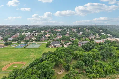 an aerial view of residential houses with outdoor space and trees