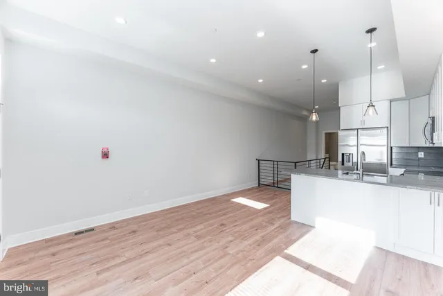 a view of a kitchen with kitchen island a sink wooden floor and a counter top space