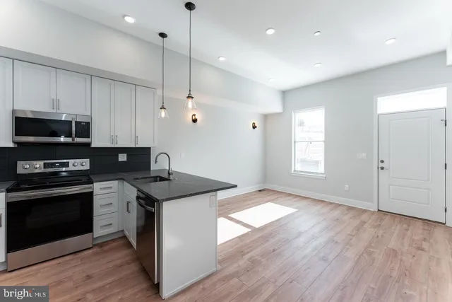 a kitchen with stainless steel appliances granite countertop a sink a stove a refrigerator and a microwave