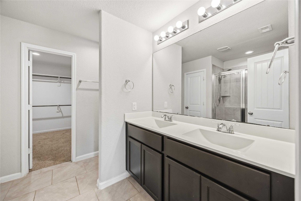 703 Autumn Flats Way Rosharon, TX 77583 - Photo 10 of 18 We have a double vanity that offers plenty of personal space, topped with a clean white counter and integrated sinks. It also shows the massive walk-in closet directly accessible from bath.The oversized walk-in closet provides abundant shelving and hanging space to keep your wardrobe organized.