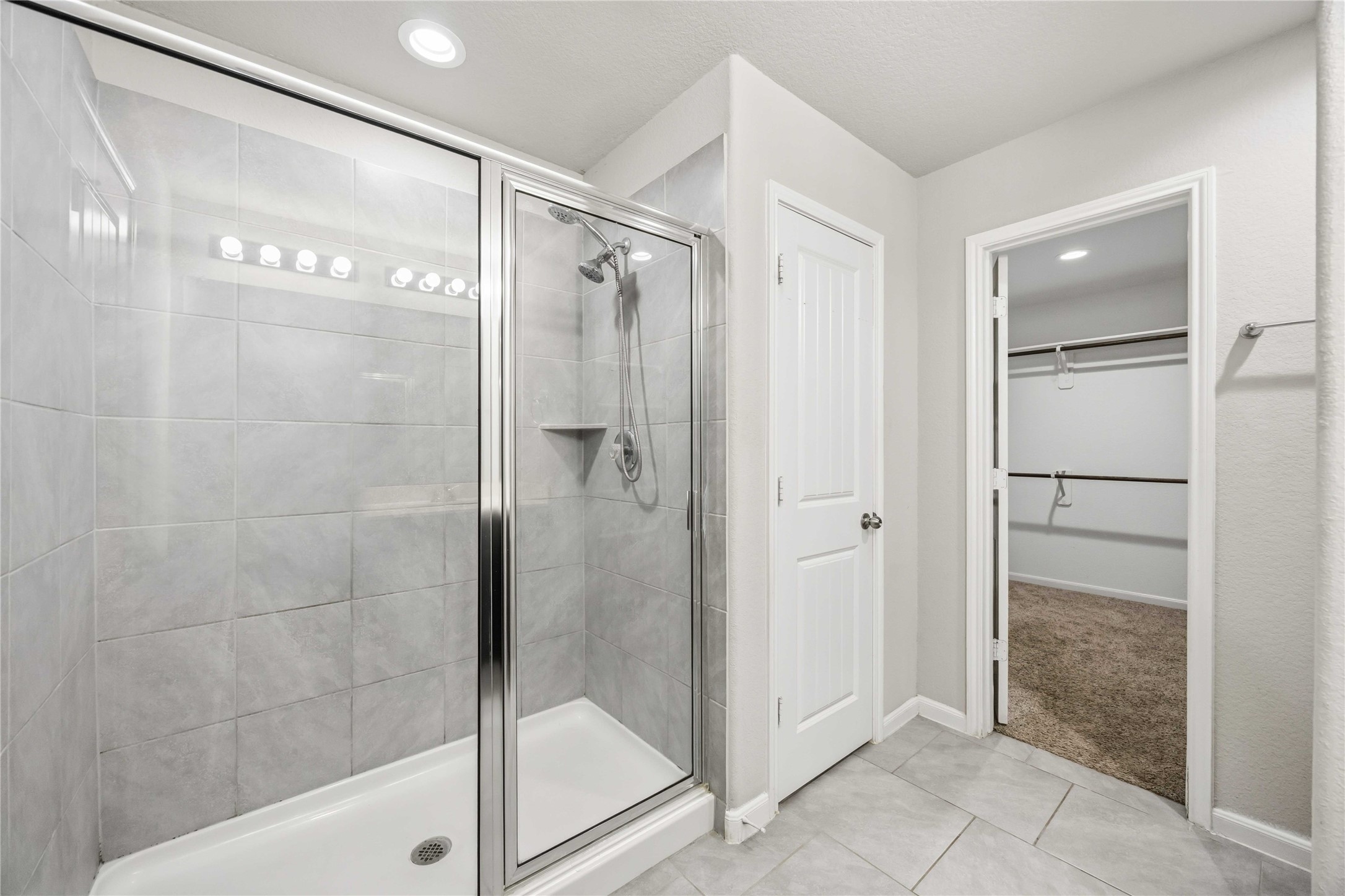 703 Autumn Flats Way Rosharon, TX 77583 - Photo 11 of 18 Features a large, glass-enclosed shower adorned with contemporary grey tiling, complete with a built-in corner shelf for convenience.