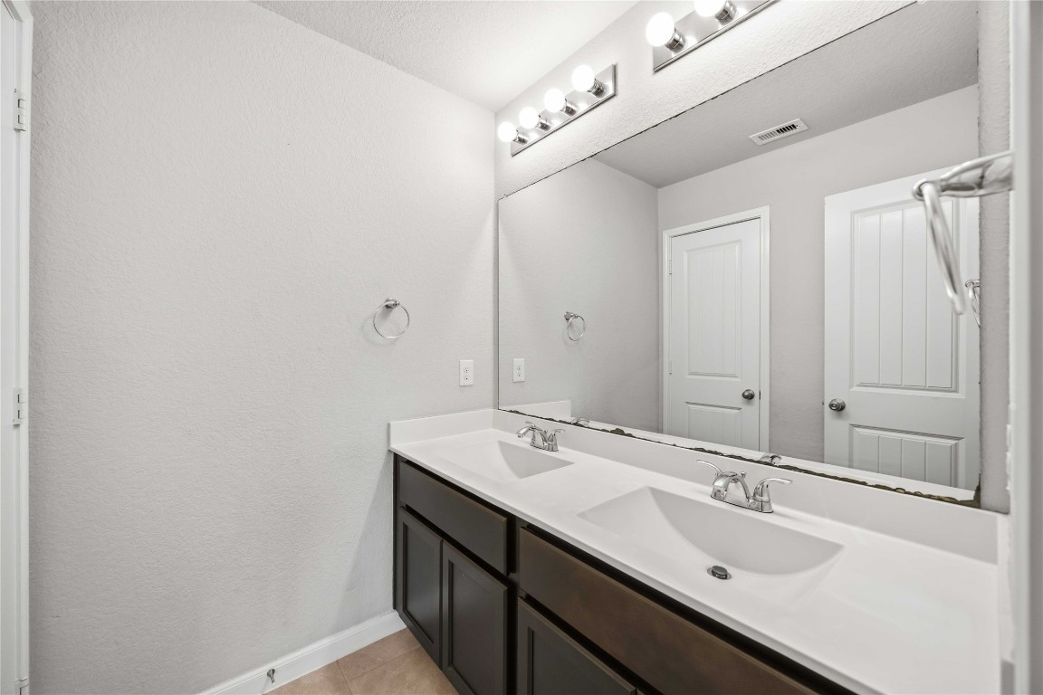 703 Autumn Flats Way Rosharon, TX 77583 - Photo 14 of 18 Clean lines and functional design define this secondary bath. It boasts an oversized mirror, bright vanity lighting, and dual sinks.