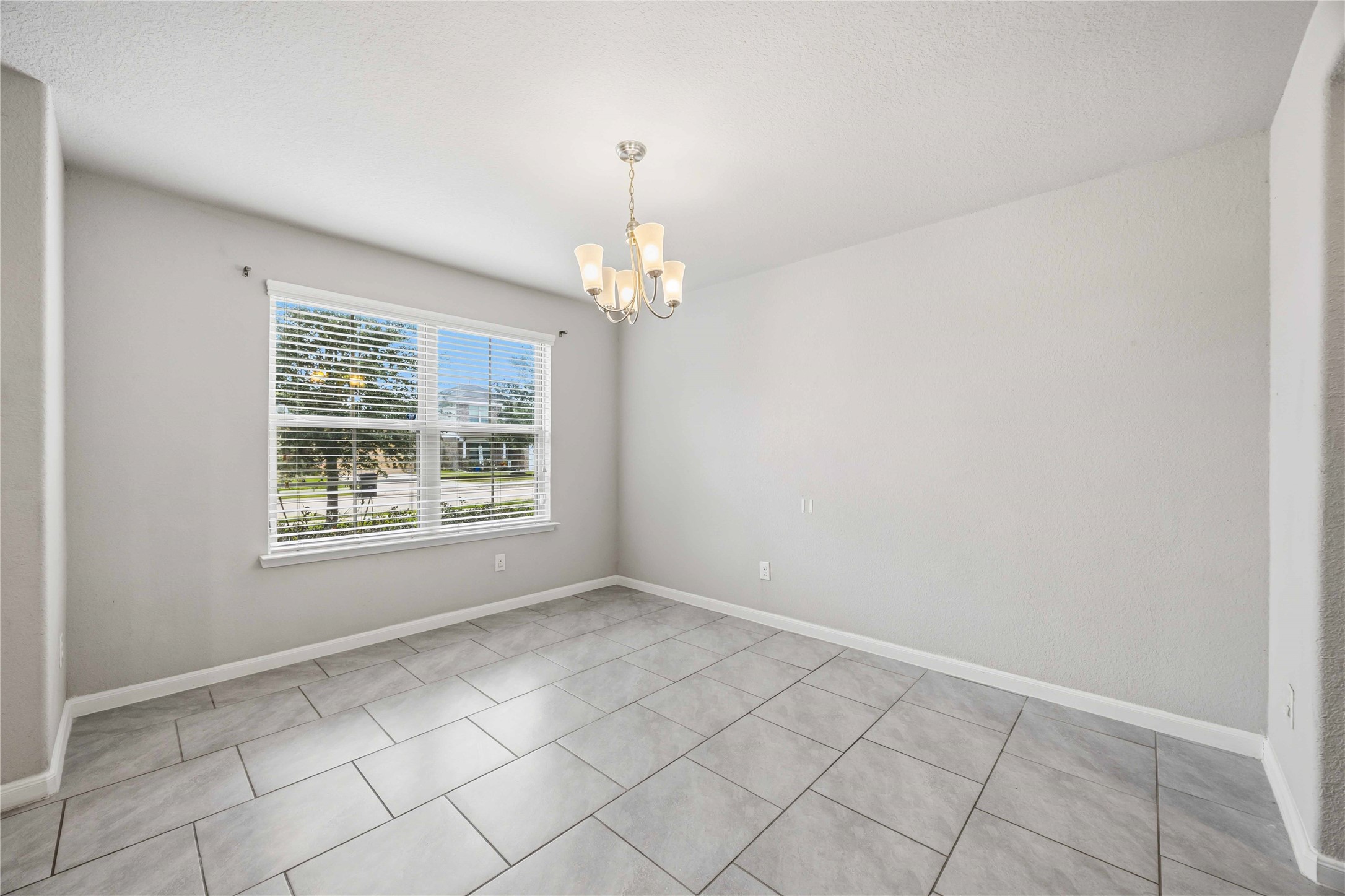 703 Autumn Flats Way Rosharon, TX 77583 - Photo 2 of 18 A bright and airy versatile room, ideal for a formal dining area with a large window equipped with classic white blinds floods the space with natural light. Centered in the room is a stylish five-light chandelier with frosted shades, adding a touch of elegance and warmth to your evening gatherings