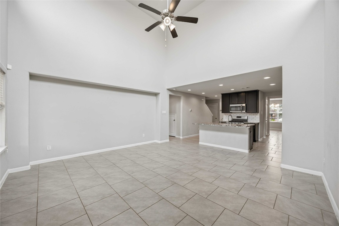 703 Autumn Flats Way Rosharon, TX 77583 - Photo 17 of 18 The expansive living room transitions smoothly into the modern kitchen, making it an entertainer's dream and a perfect setup for busy mornings. This alternative view highlights the superb open-concept floor plan, demonstrating how the grand living area flows effortlessly into the heart of the home.