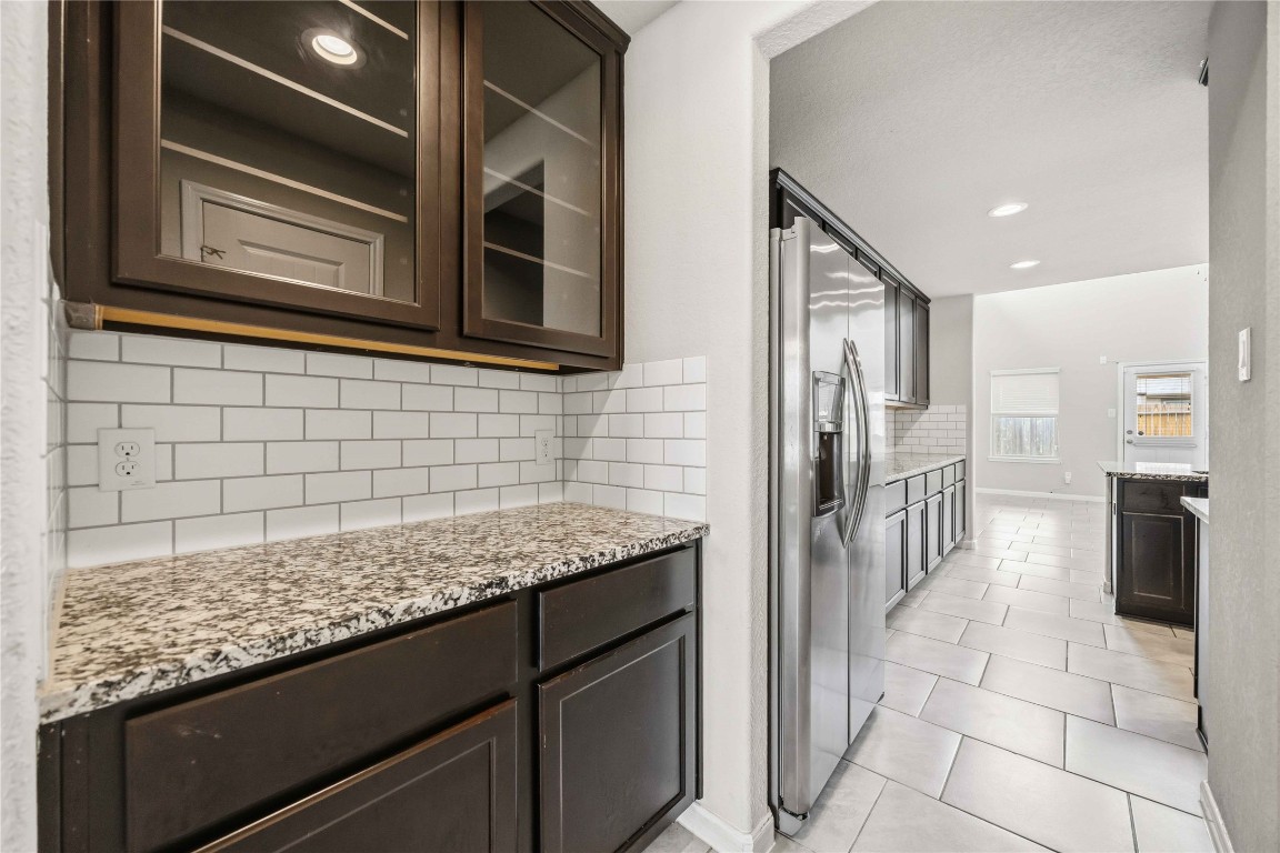 703 Autumn Flats Way Rosharon, TX 77583 - Photo 6 of 18 Enhance your hosting capabilities with this sophisticated butler’s pantry, seamlessly connecting your dining and kitchen areas. This highly functional space offers the perfect staging area for dinner parties or a dedicated coffee and wine station. Cabinetry features glass-front upper cabinets with integrated shelving and interior lighting, perfect for showcasing fine china or glassware.