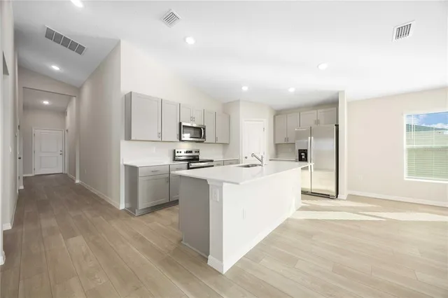 a large kitchen with a center island wooden floor stainless steel appliances and windows