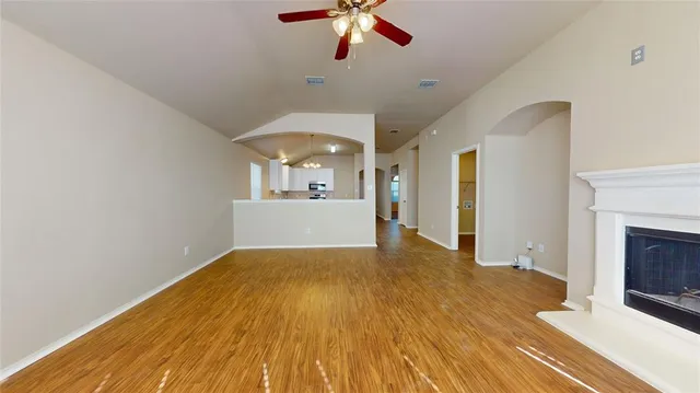 a view of a livingroom with a fireplace a chandelier fan and wooden floor