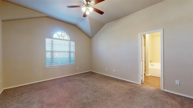 an empty room with chandelier fan and windows