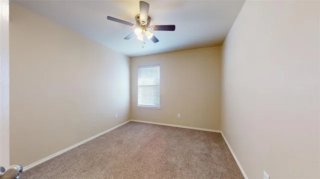 an empty room with a chandelier fan and windows