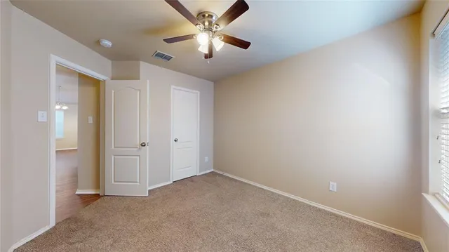 an empty room with chandelier fan and closet