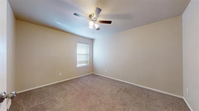 a view of an empty room with chandelier fan