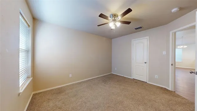 an empty room with windows and fan