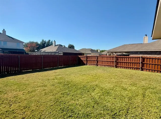 a view of a yard with wooden fence