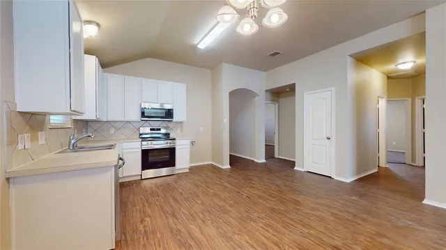 a large kitchen with cabinets wooden floor and stainless steel appliances