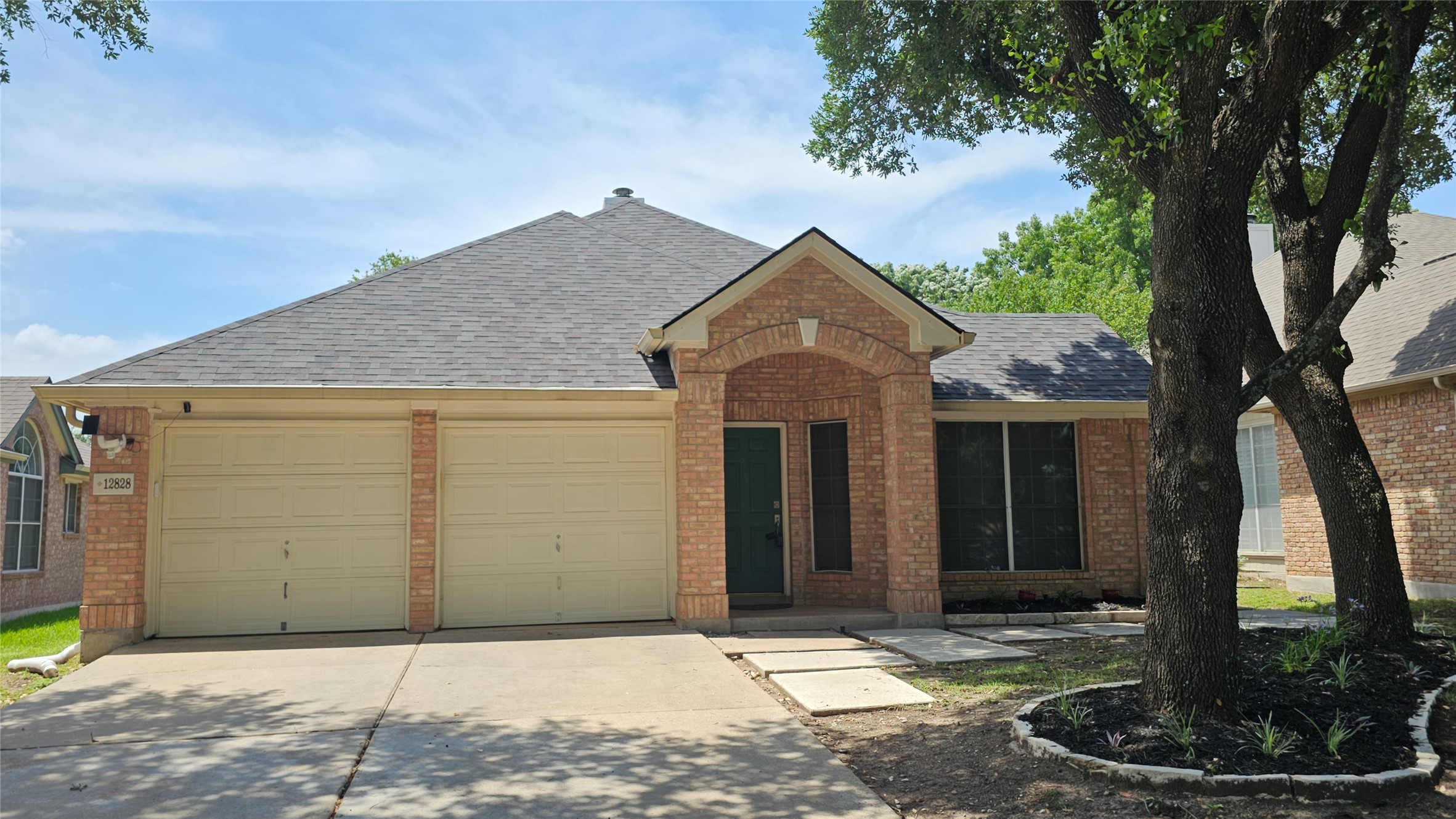 12828 Withers Way Austin, TX 78727 - Photo 1 of 1 View of front facade featuring brick siding, driveway, an attached garage, and a shingled roof