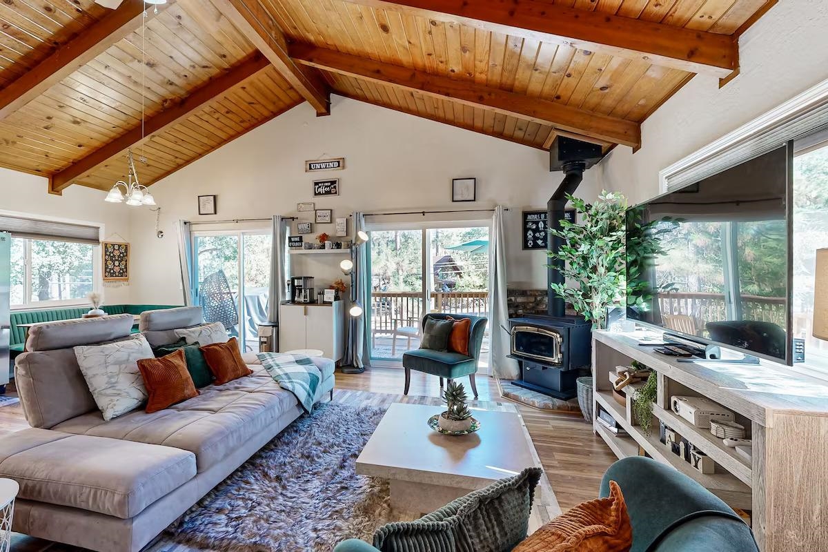 19385 Ferretti Road Groveland, CA 95321 - Photo 4 of 47 Living area featuring a wood stove, high vaulted ceiling, wood finished floors, a wooden ceiling with exposed beams, and a chandelier