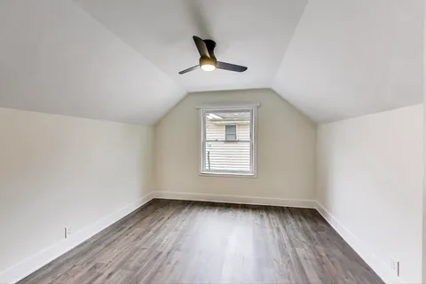 an empty room with wooden floor ceiling fan and window