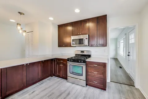a kitchen with stainless steel appliances granite countertop wooden cabinets and a stove top oven
