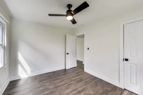 an empty room with wooden floor cabinet and windows
