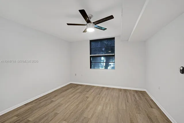 a view of empty room with wooden floor and ceiling fan