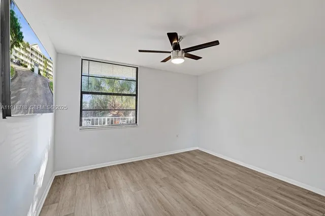 a view of empty room with wooden floor and fan