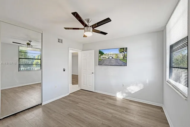 a view of empty room with wooden floor and fan