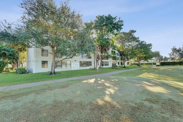 a view of a house with a big yard and large trees