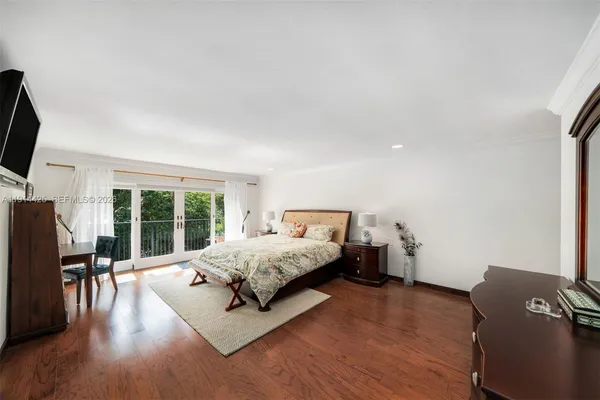 a spacious bedroom with a bed and wooden floor