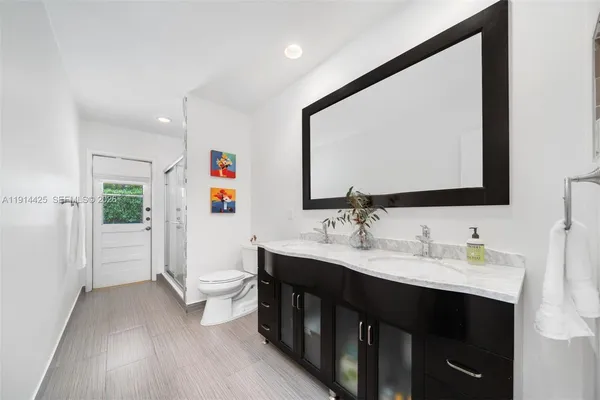 a en suite bathroom with a double vanity sink toilet and a mirror