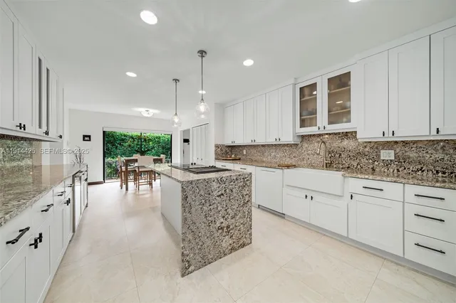 a kitchen with stainless steel appliances granite countertop a stove a sink a oven and white cabinets