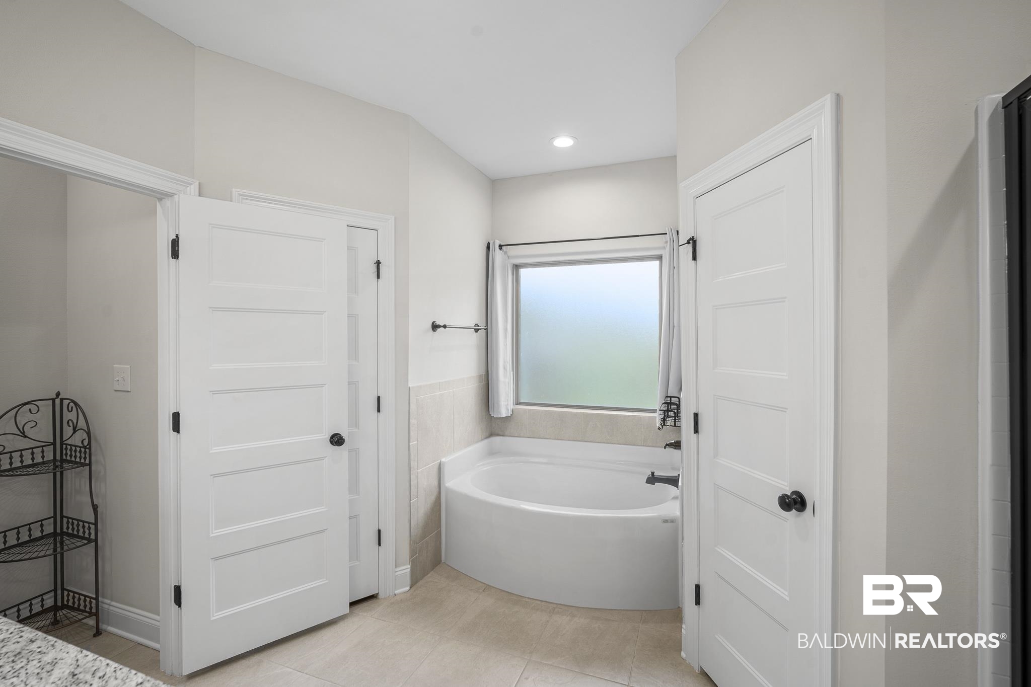 12672 Squirrel Drive Daphne, AL 36527 - Photo 23 of 49 White panel doors, a corner soaking tub, a frosted window, and light-toned tile flooring