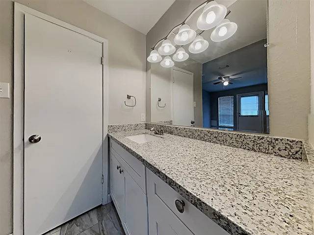 a bathroom with a granite countertop sink and a large mirror